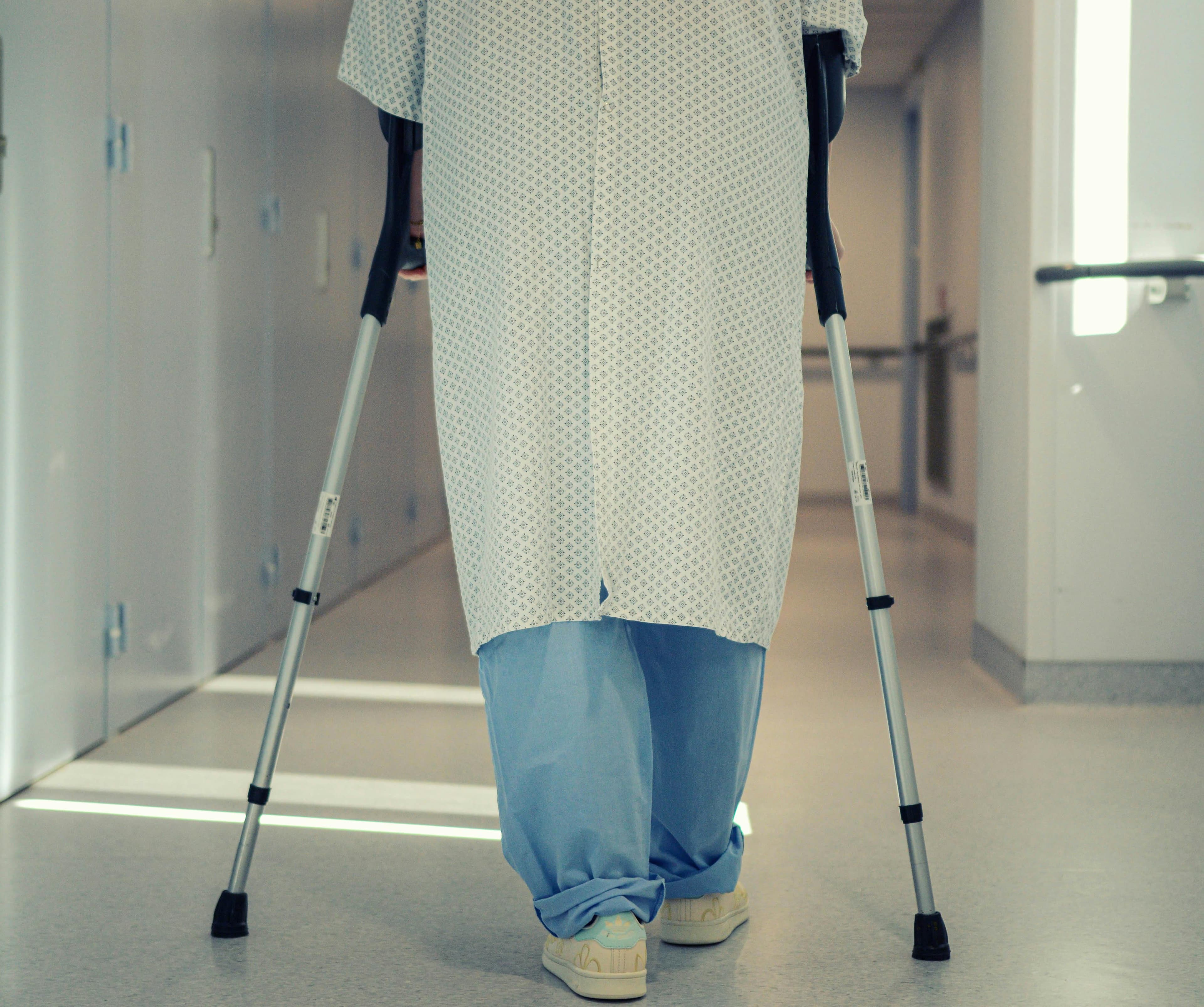 A patient walking a clinic corridor on crutches during orthopedic recovery